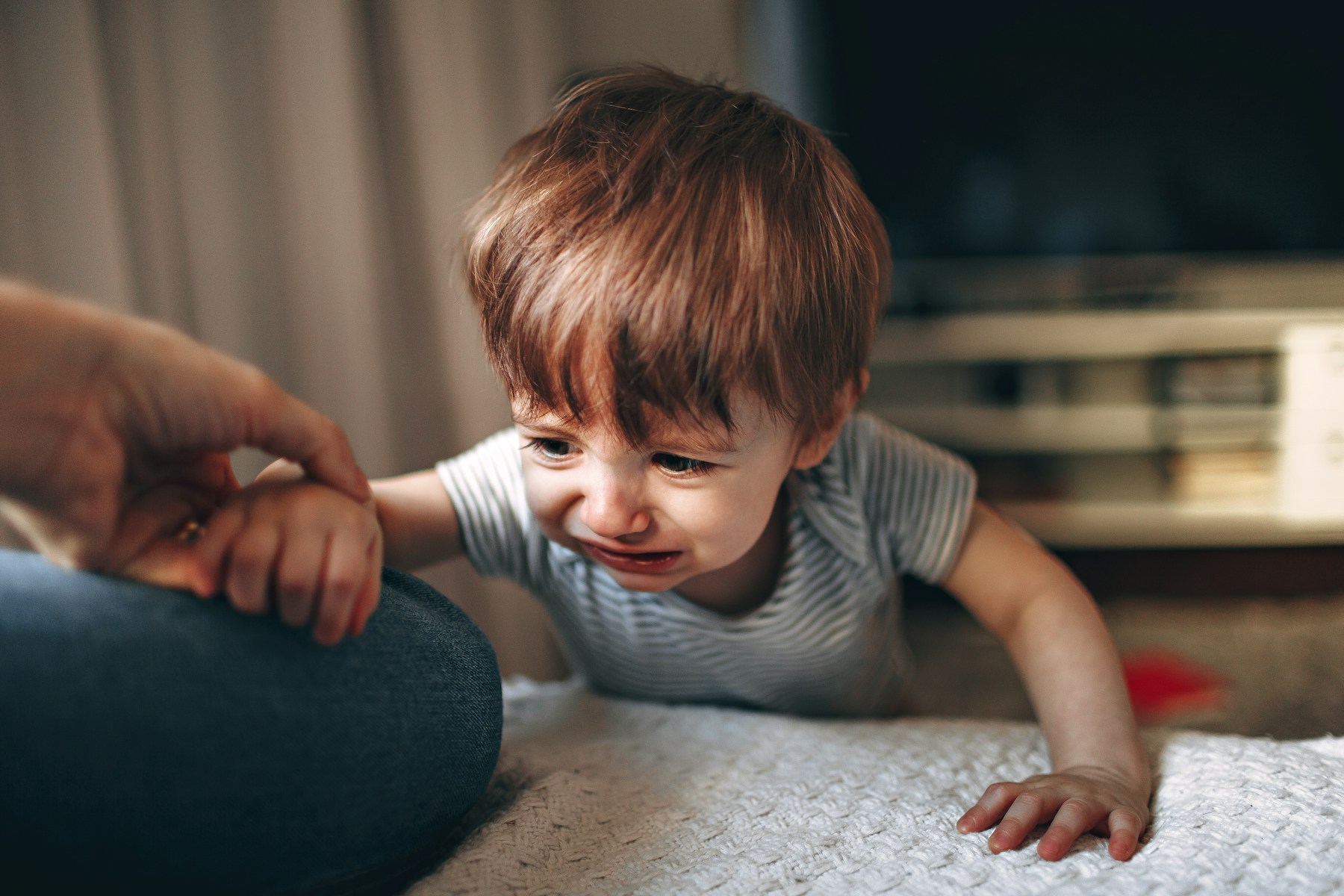 An upset toddler holding a parent’s hand during a big-feelings moment, photographed by Helena Lopes on Unsplash.